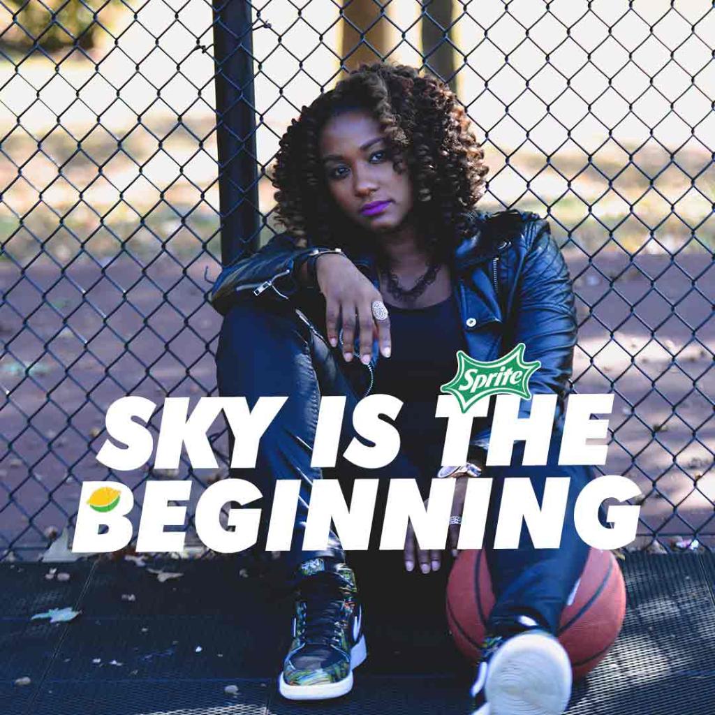 music artist with basketball in front of fence with text 'sky is the beginning'